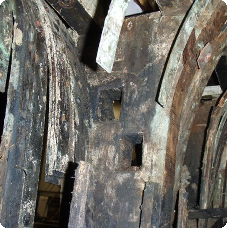 Close-up of weathered, aged wooden beams and arch-like structures with rectangular holes, displaying signs of rot and wear—reminiscent of the craftsmanship found in Classic Sailing Yachts or historic Square Metre Yachts.