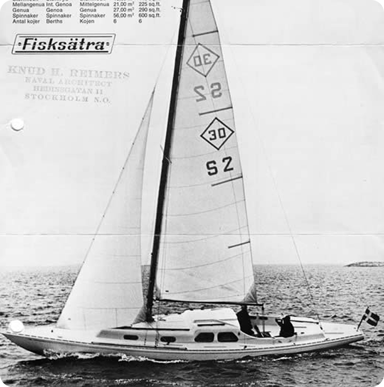 Black-and-white photo of a Skerry Cruiser sailboat with two people on board, sailing on open water. The sail displays the numbers DE 30 S2. This classic sailing yacht appears to be moving at a moderate speed.