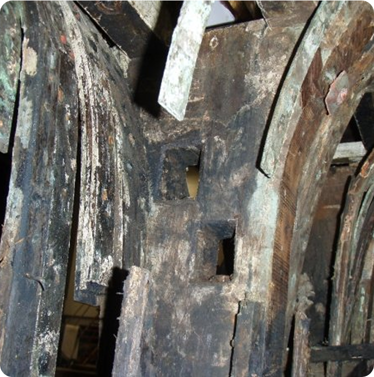 Close-up of weathered wooden beams, with square holes and greenish discolouration, reminiscent of the aged construction found on Classic Sailing Yachts or elegant Square Metre Yachts, showing signs of age and damage.